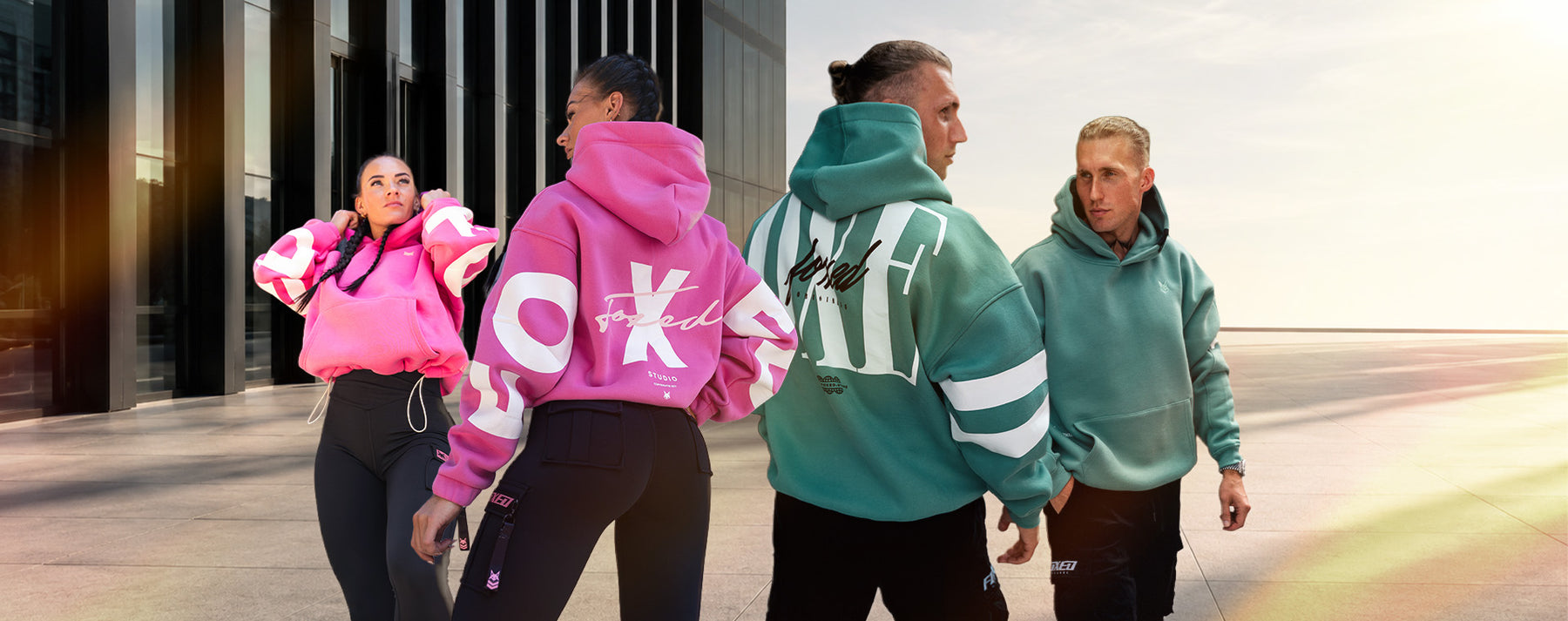 Vier Personen in Foxed-Hoodies und -Hosen vor einer Glasfassade.